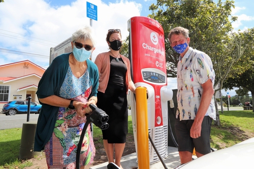 Three people by EV charger.