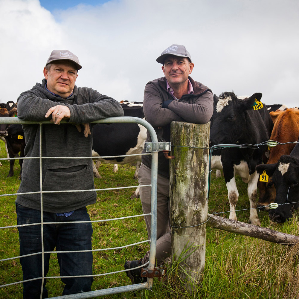 Two men leaning on a fence.